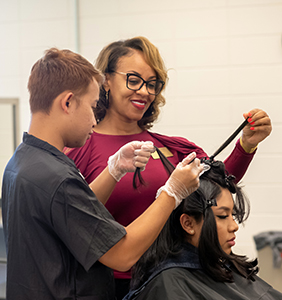 An instructor helps a student in the cosmetology program.